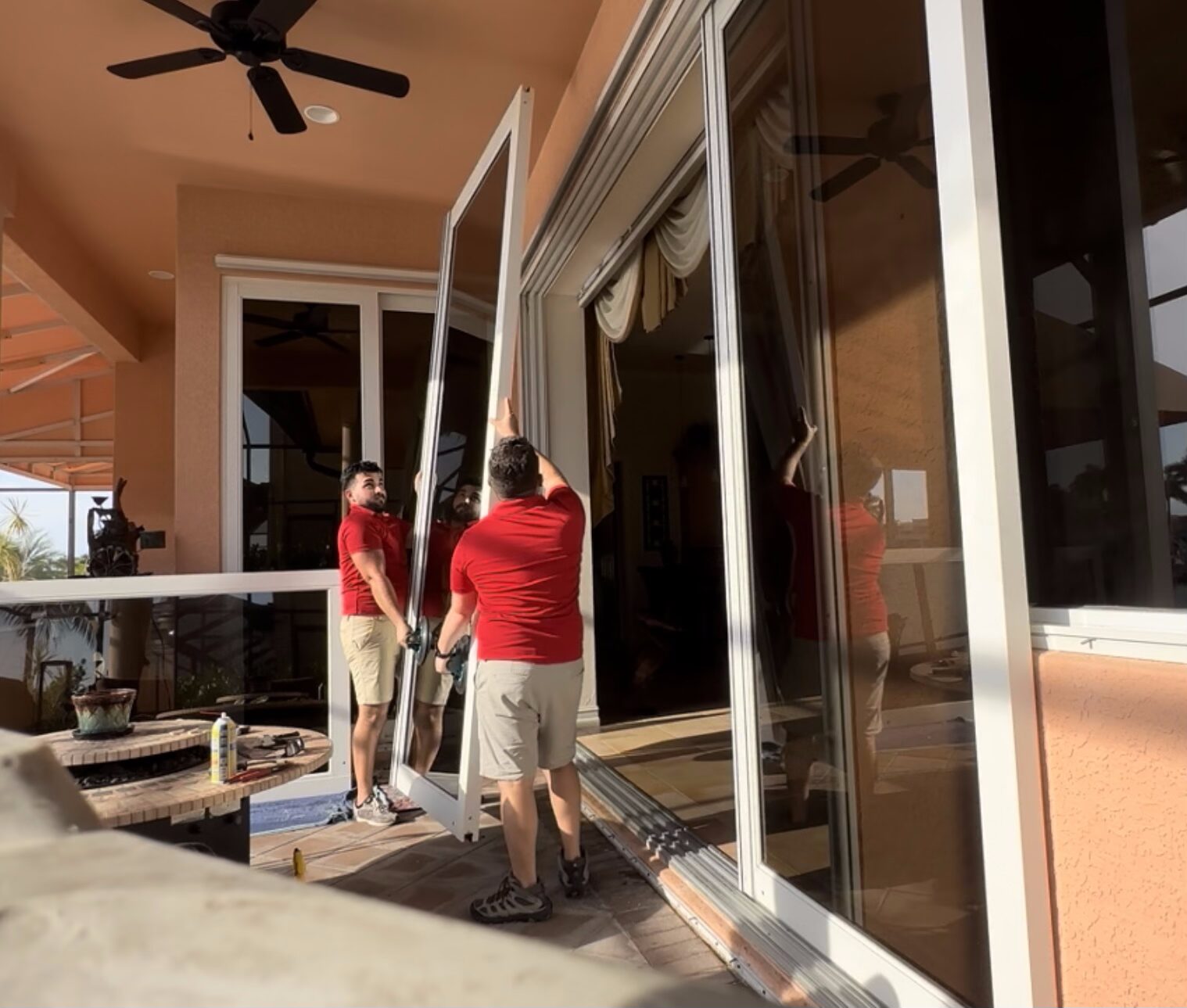 tempImagefSGdfF Two men installing large glass door.